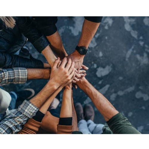 Manos de un equipo unidas sobre una mesa, símbolo de colaboración y trabajo conjunto